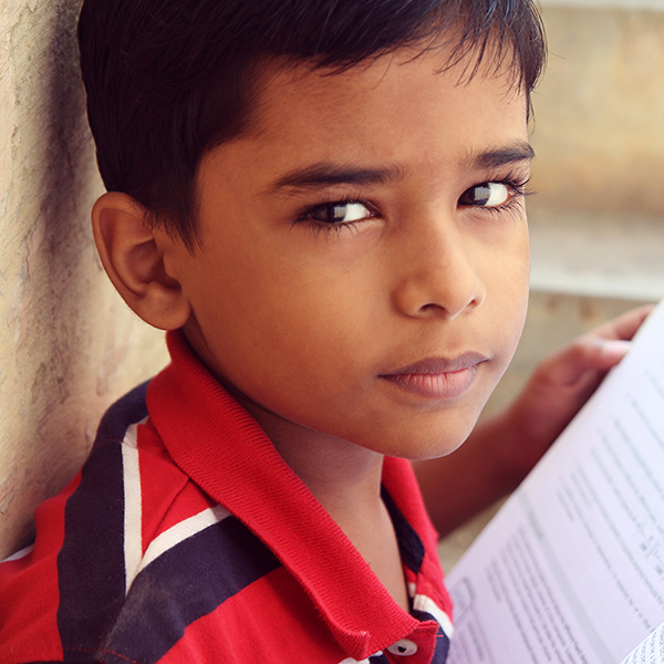 A young boy reading, looking thoughtfully at the camera